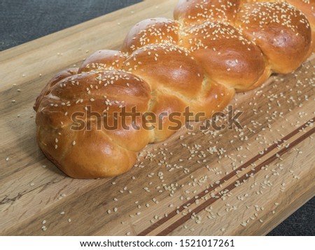 Challah bread, a special bread in Jewish cuisine, usually braided and typically eaten on ceremonial occasions such as Shabbat and major Jewish holidays. With wooden cutting board and seseame seeds
