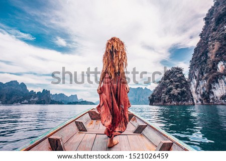 fashionable young model in boho style dress on boat at the lake 