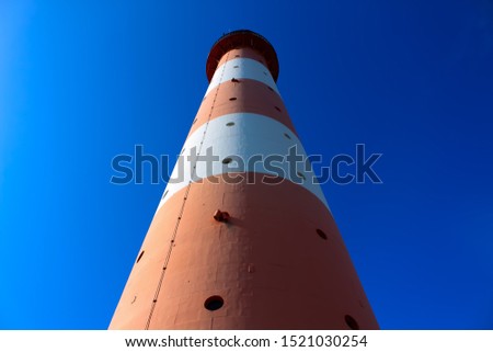 A simple shot of a lighthouse with clear blue sky. The light and shadows divide the picture in two.