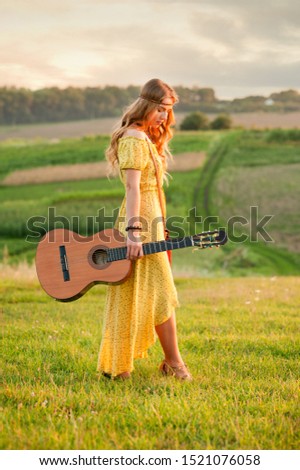 girl in yellow dress bohemian style, holding a guitar on the field with a warm and comfortable atmosphere sunset