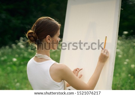 woman easel paints a picture white canvas nature