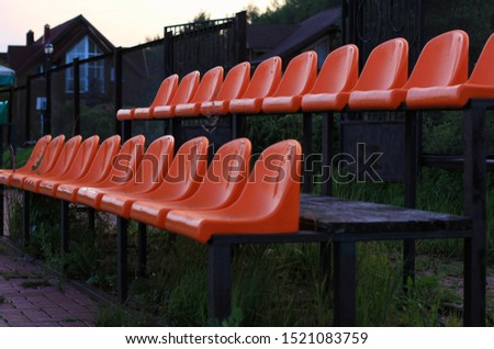 rows of empty orange seats or chairs for fans at a street football stadium