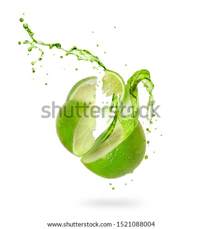 Juice splashes out of a cut lime on a white background