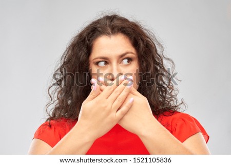 emotion, expression and people concept - scared woman in red dress closing her mouth by hands over grey background
