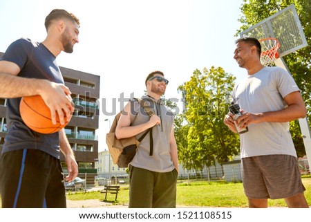 sport, leisure games and male friendship concept - group of men or friends going to play basketball outdoors
