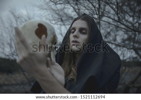 Close-up man with eyes closed holding a skull