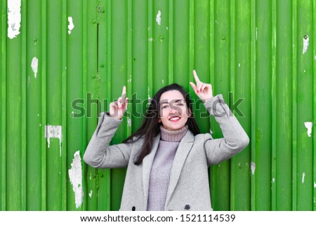 girl on a green background. In a warm gray coat. Portrait of the beautiful girl on a green background