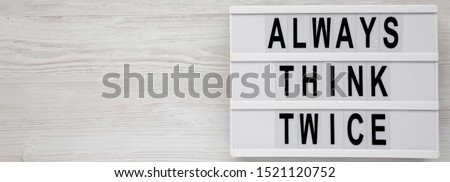 'Always think twice' words on a lightbox on a white wooden surface, top view. Overhead, from above, flat lay. Copy space.