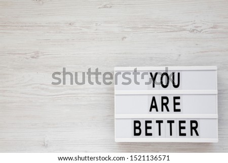 'You are better' words on a lightbox on a white wooden surface, top view. Overhead, from above. Flat lay. Space for text.
