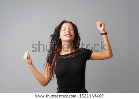 Happy young woman showing victory sign over gray background Royalty-Free Stock Photo #1521163469