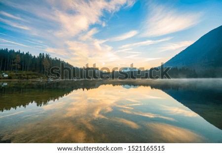 Amazing morning scenery on Hintersee lake. Picturesque clouds coloured by rising sun and reflected in surface water, Bavaria, Germany