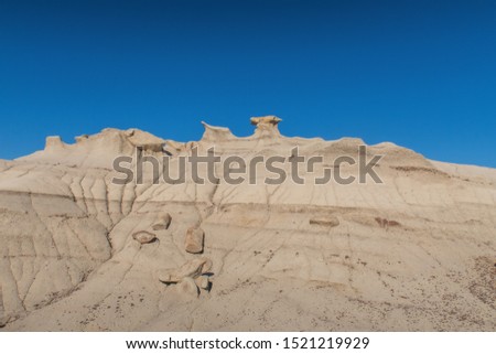 Bisti Badlands low angle landscape of grey stone hill with small hoodoo stones on top