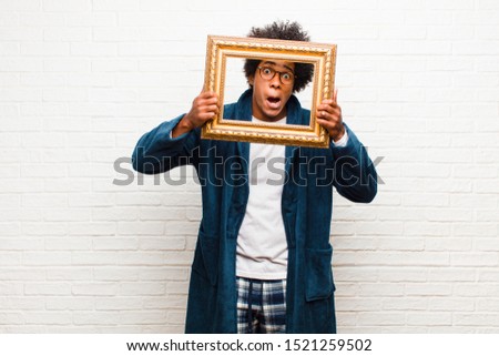 young black man with a baroque frame at home