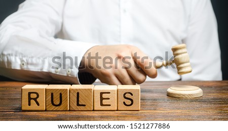 A man knocks a hammer publishes new rules and laws. Setting clear rule and restrictions. Leadership and discipline. Authoritarianism, tight control framework. Norms and laws in society, state Royalty-Free Stock Photo #1521277886