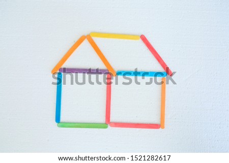 Ice cream sticks of various colors arranged in a house shape.