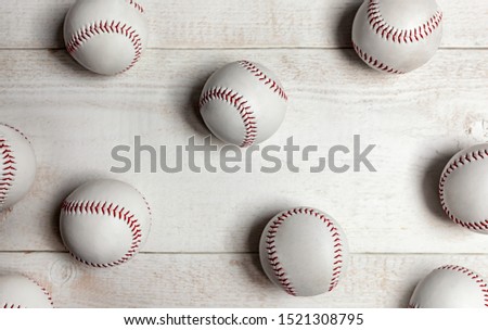 Many baseball or softball balls on white wooden background.