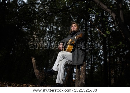 A young man with a guitar in late evening with contour light