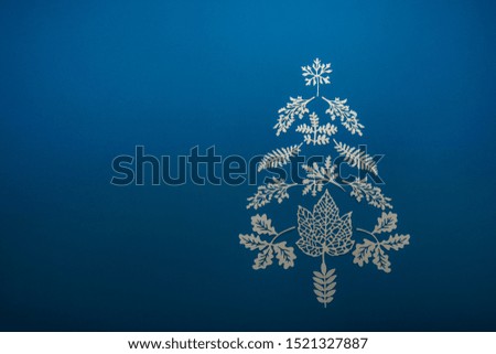 Christmas tree of carved paper tree leaves on a blue background
