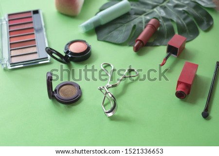 A collection of make up and cosmetic products arranged on a pastel green background.beauty concept.