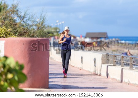 Young smiling girl jogging on the embankment in the morning. Healthcare lifestyle image with copy space