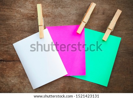 blank paper note color white green pink with paper clip on wood background.