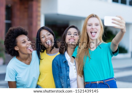 Group of multi ethnic young adult woman taking crazy selfie outdoor in summer in city