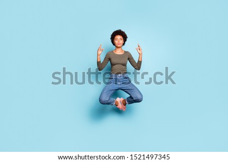 Full length photo of beautiful dark skin wavy lady jumping high sitting air in lotus pose practicing morning yoga wear casual outfit isolated pastel blue color background