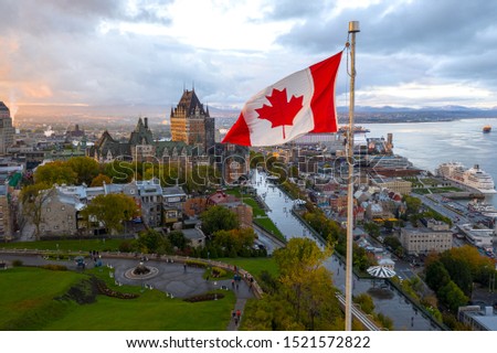 A Canadian flag flies high at sunset with Old Quebec City, Canada and the Saint Lawrence seaway in the background Royalty-Free Stock Photo #1521572822