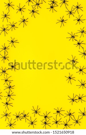 Minimalistic Halloween frame with small spiders on yellow background top view copy space