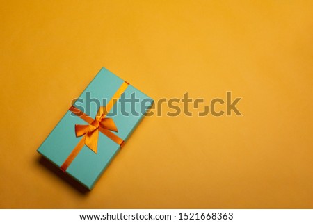 Green Christmas gift box on yellow background flat lay