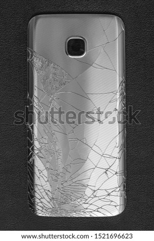 Broken smart phone on black background. Back view. Repair device, mobile cellphones concept. Gadget dropped