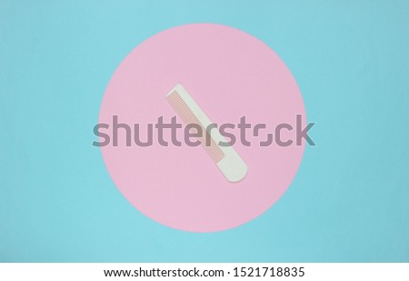 White Hair combon on blue pastel background with pink pastel circle. Creative minimalistic beauty and fashion still life. Top view
