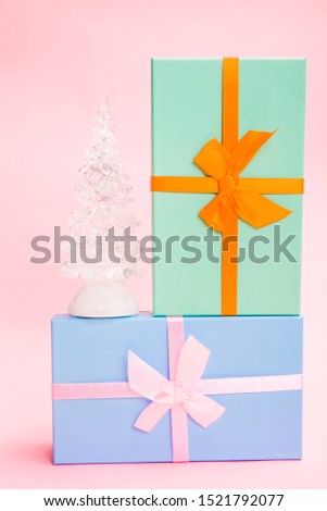 glass white Christmas tree with gifts with bows on a pink background