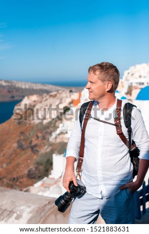 Man photographer taking pictures of Santorini, Greece. Shooting. Camera.