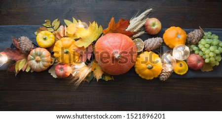 Fall decor for Thanksgiving Day with pumpkins, leaves, apples, lights on wooden table. View from above. Horizontal orientation. Centerpieces Thanksgiving.