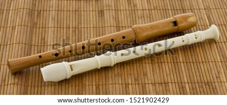 Two block flute, recorders in different colours on a brown table mat Royalty-Free Stock Photo #1521902429