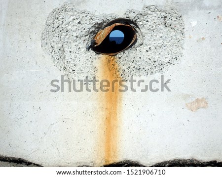 Hole on concrete wall resembling an evil eye