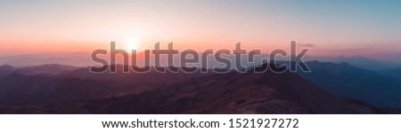 Beautiful mountain landscape with sunset over Taurus Mountains from the top of Tahtali Mountain near Kemer, Antalya, Turkey. Photo in orange and blue natural tones. Royalty-Free Stock Photo #1521927272