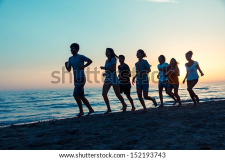 Group of People Running on the Beach at Sunset