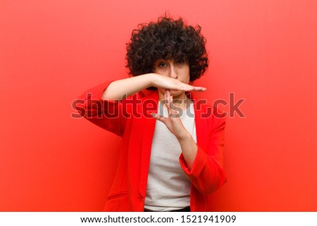 young pretty afro woman looking serious, stern, angry and displeased, making time out sign