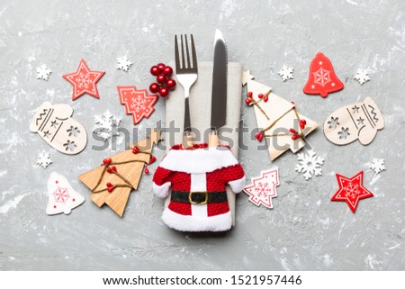 Top view of fork and knife tied up with ribbon on napkin on cement background. Close up of christmas decorations and New Year tree. Happy holiday concept.
