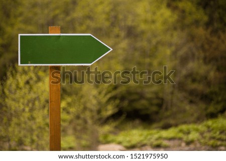 Blank green directional arrow sign on nature background. Wooden sign board