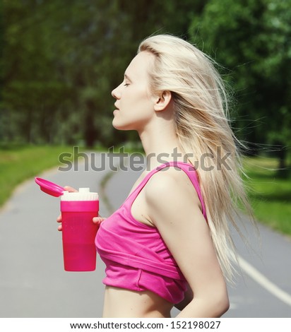 Sporty woman with pink plastic bottle of water after running in pink t-shirt