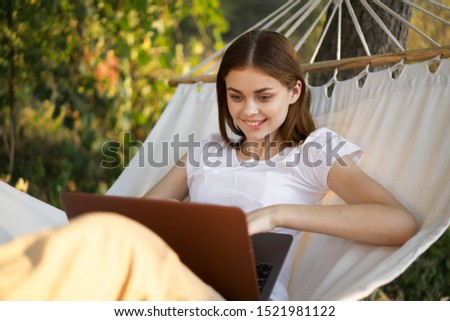 beautiful woman model working outdoors in a hammock with a laptop