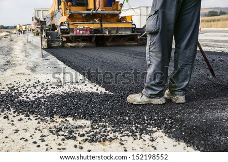 Worker operating asphalt paver machine during road construction and repairing works Royalty-Free Stock Photo #152198552