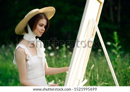 woman with a white canvas in the open air draws