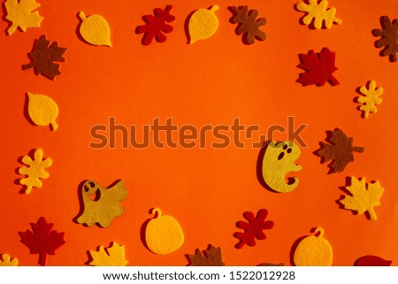 Autumn leaves and two ghosts are laid out on a bright orange background. Concept for the holiday Halloween.

