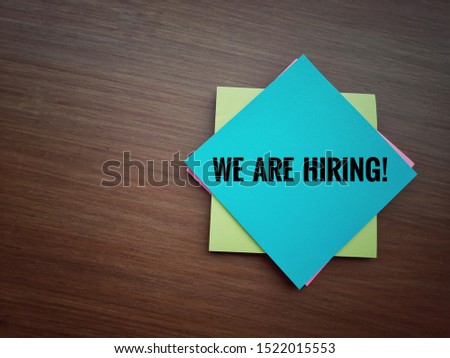 We are hiring wording on office sticky notes over dark wooden background