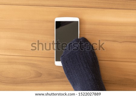Feet of a man stepping on a dropped smartphone