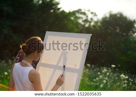 young woman model with a brush in hand with a white canvas